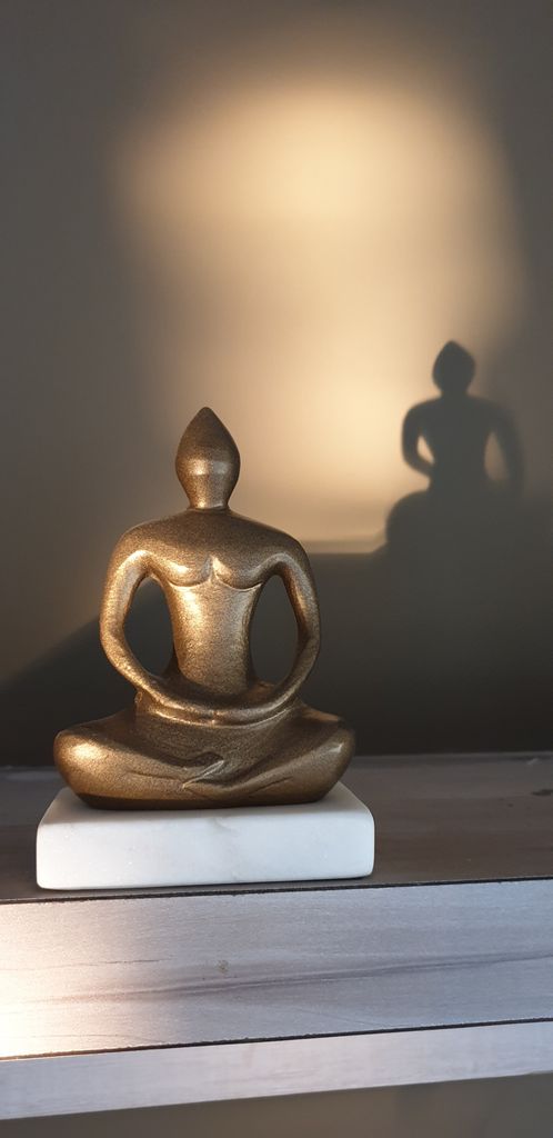 A golden Buddha figurine with a serene shadow adds a touch of calm and elegance to the decor.